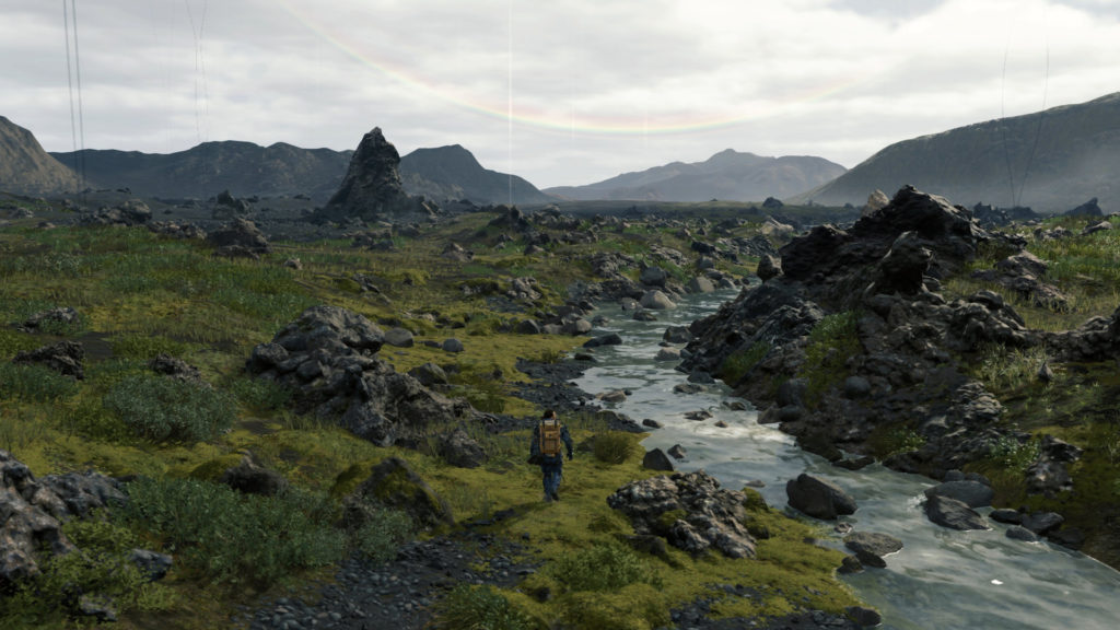 Death Stranding: Norman Reedus walking next to river in futuristic landscape