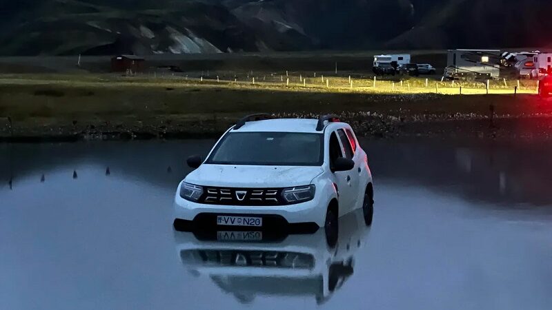 A white car tyre-deep in a lake.