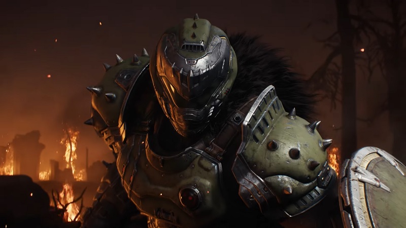 Doom The Dark Ages: A close-up of the Doom Slayer holding a shield with fire behind him.
